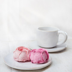 Sweet dessert under rays of morning sun. Berry marshmallows and cup of coffee. Pleasant moments.