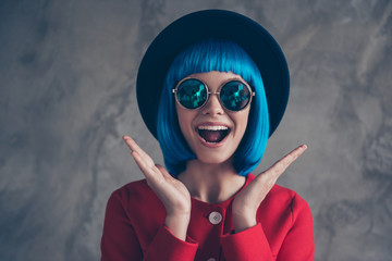 Wow! Portrait of glad excited girl in eyeglasses blue wig holding two palms near face with wide open mouth isolated on grey background