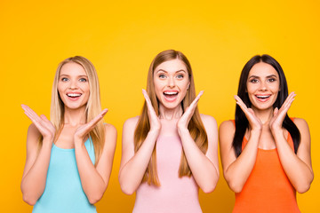 Sticker - Great! Portrait of amazed pleased trio holding palms near face having good news information isolated on vivid yellow background