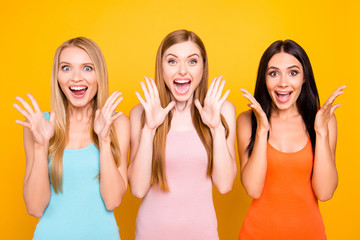 Wall Mural - Portrait of mad funny girls yelling with wide open mouth full of happiness gesturing with palms enjoying seasonal discounts isolated on bright yellow background