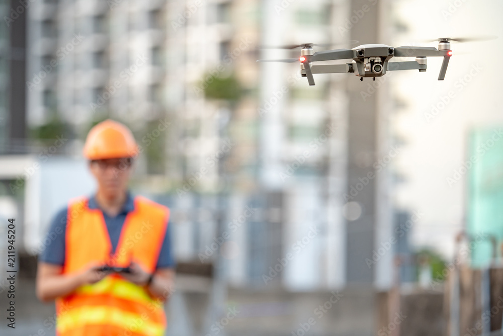 Young Asian engineer flying drone over construction site. Using ...