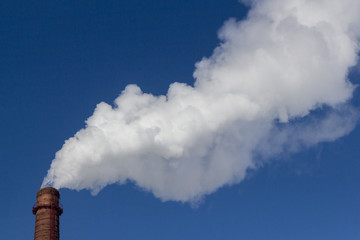 White smoke comes from the old brick factory chimney. Concept Industry and environmental protection.