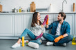 © LIGHTFIELD STUDIOS - couple sitting on floor and giving high five after cleaning in kitchen