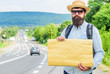 © be free - Man bearded hitchhiker stand at edge of road with blank paper sign, copy space. Benefits using sign with name destination. Cardboard sign with indication where you want go. Short general directions