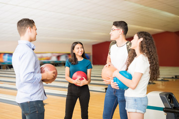 Friends Communicating While Having Fun At Bowling Alley