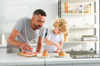 © LIGHTFIELD STUDIOS - focused little boy with father putting strawberry pieces on pancakes at kitchen