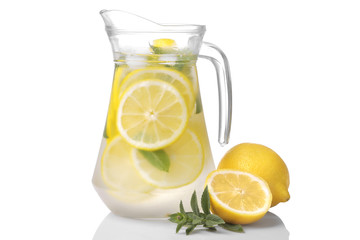 Homemade lemonade with mint and ice in a glass jug and a glass next to fresh lemon on a white background. isolated...