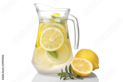 Cuadros en Lienzo Homemade lemonade with mint and ice in a glass jug and a glass next to fresh lemon on a white background