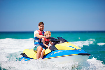 Wall Mural - happy, excited family, father and son having fun on jet ski at summer vacation