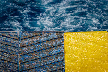 Wall Mural - Colorful closed ferry ship door with the white water generated by the engines in the background