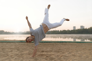 Wall Mural - Athletic capoeira performer workout training on the beach sunris