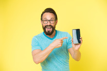 Check Out New App. Guy Eyeglasses Cheerful Pointing At Smartphone. Man Happy User Recommends Try Application For Smartphone. Man Takes Advantages Online Communication. Guy Bearded Smartphone User