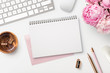 Leinwandbild Motiv feminine workspace / desk with blank open notepad, keyboard, stylish office / writing supplies and pink peonies on a white background, top view