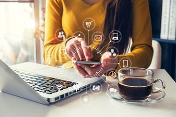  woman using smart phone for mobile payments online shopping,omni channel,sitting on table,virtual icons graphics interface screen in morning light