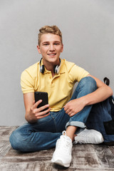 Canvas Print - Portrait of a smiling casual teenage boy with backpack sitting