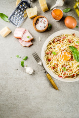 Wall Mural - Traditional italian pasta, spaghetti carbonara with bacon, creamy sauce, parmesan cheese, egg yolk and fresh basil leaves grey stone background copy space