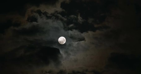 a glowing full moon in the dark and cloudy night