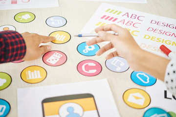 Wall Mural - crop shot of coworking man and woman choosing colorful icon for mobile application while creating ne