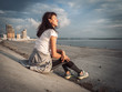 Sports lifestyle: The girl is sitting on the city embankment. A breather after jogging. Sunset.