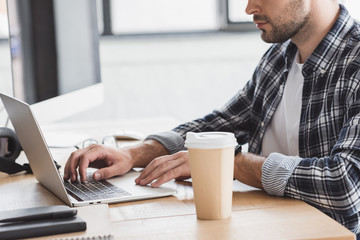 cropped shot of young man using laptop at workplace