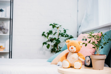 Wall Mural - teddy bear with plant and alarm clock in front of bed