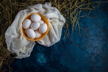 White Chicken Eggs In Yellow Plate, Hay On A Blue Background. The Concept Of A Natural Product. Copy Space. Flat Lay, Top View