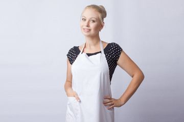 Wall Mural - cute blonde woman in white apron posing on white background. cook. a housewife