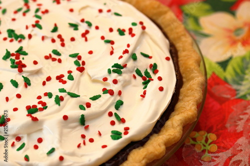 Fotografia, Obraz A smooth and silky fudge pie topped with whipped cream and holly berry sprinkles for Christmas dinner