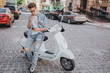 © estradaanton - Handsome guy is sitting on motorcycle and holding phone in hand. He is looking at it. Theere is a cigarette in other hand. He is smoking.