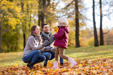 Sticker - family, season and people concept - happy mother, father and little daughter with maple leaves at autumn park