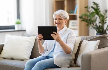 technology, age and people concept - happy senior woman with tablet pc computer at home