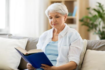 Canvas Print - age, leisure and people concept - senior woman reading book at home