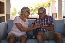 Senior Couple Checking Blood Sugar With Glucometer In Living