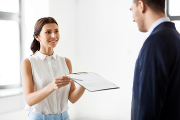 Poster - real estate business, sale and people concept - female realtor with clipboard showing contract document to customers at new office room