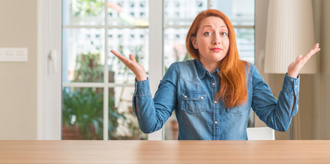 Sticker - Redhead woman at home clueless and confused expression with arms and hands raised. Doubt concept.