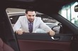 © Wavebreak Media - Portrait of confident salesman examining car
