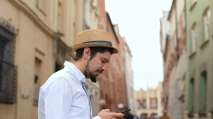 outside portrait of elegant brunette man using smartphone mobile on the street and thoughtful lookin