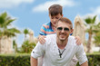 © Artem - Cute european boy is riding his father. Theyare having fun at the green lawn of the hotels territory.