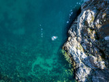Fototapeta Do pokoju - directly above view of man swimming in the water mattress near the rock on a summer vacation
