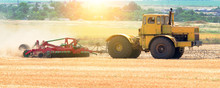 Yellow Tractor At Sunset Works On Field Disco After Harvesting