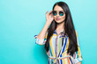 Fashion model in sunglasses , beautiful young woman isolated on blue background