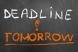 Deadline tomorrow chalk text on blackboard or chalkboard.