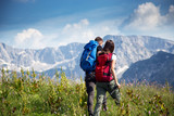 Fototapeta Las - Young couple with backpacks walking on mountain
