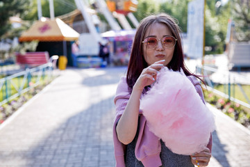 Cheerful young pretty girl with a smile eats cotton candy