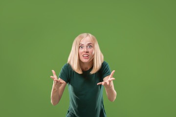 Wall Mural - Beautiful female half-length portrait isolated on green studio backgroud. The young emotional surprised woman