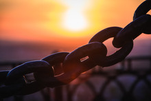 Metal Chains Of The Fence Against The Background Of The Sunrise / Sunset