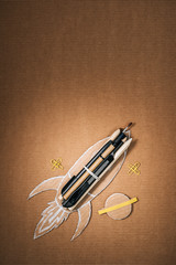 Wall Mural - top view of handmade cardboard rocket with stationery and planet on brown background