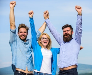 Company of three happy colleagues or partners celebrating success, sky background. Men with beard in formal shirts and blonde in eyeglasses as successful team. Company reached top. Success concept