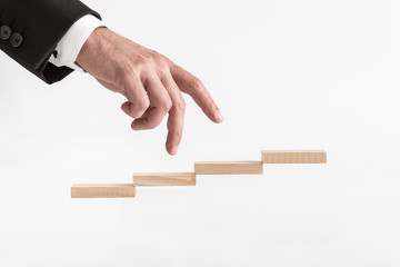 Wall Mural - Businessman walking his fingers up steps formed by wooden blocks