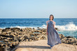 © Tatsiana - stately slender nymphet in a long dress steps neatly on the lava shore of a blue raging ocean with white foam